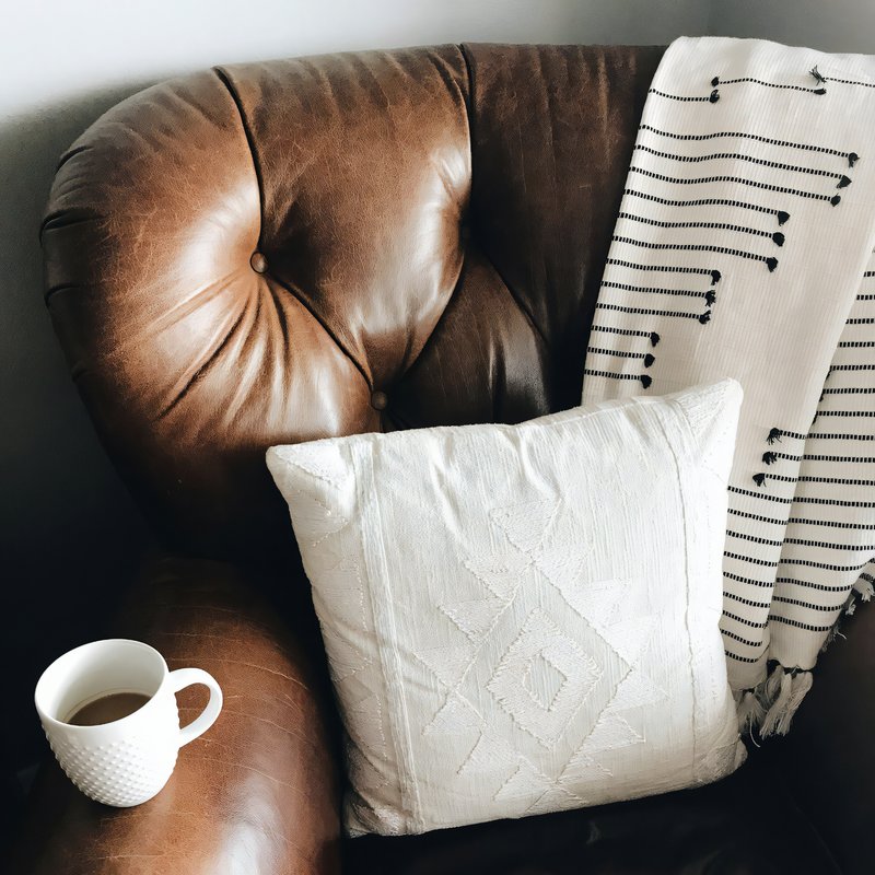 Coussin berbère blanc sur un fauteuil en cuir vintage