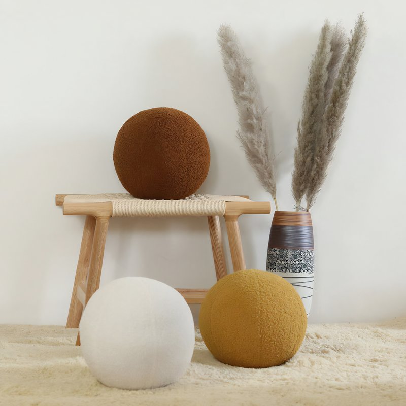 Coussins boule posés sur le sol ou sur un tabouret