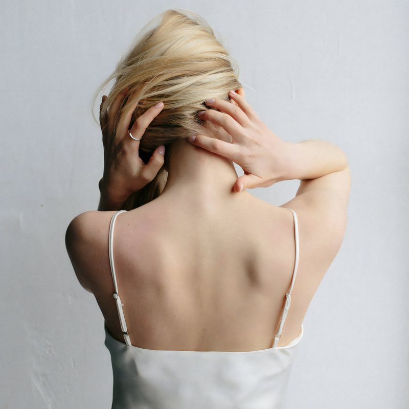 Femme de dos avec les mains au niveau des cervicales
