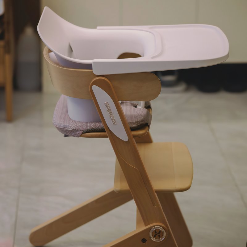 Coussin chaise haute sur une chaise haute en bois marron et en plastique rose pour bébé