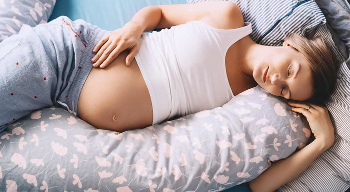 Coussin d'allaitement avec une femme enceinte allongé sur un lit