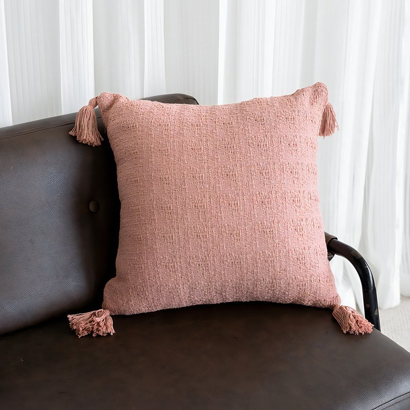 Coussin rose avec des pompons sur les 4 angles