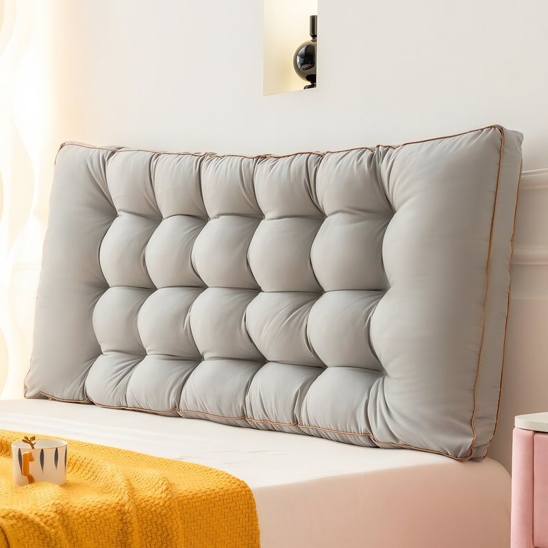 Coussin tĂȘte de lit grise posĂ© contre le mur sur un lit