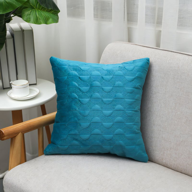 Coussin turquoise posé sur un canapé gris
